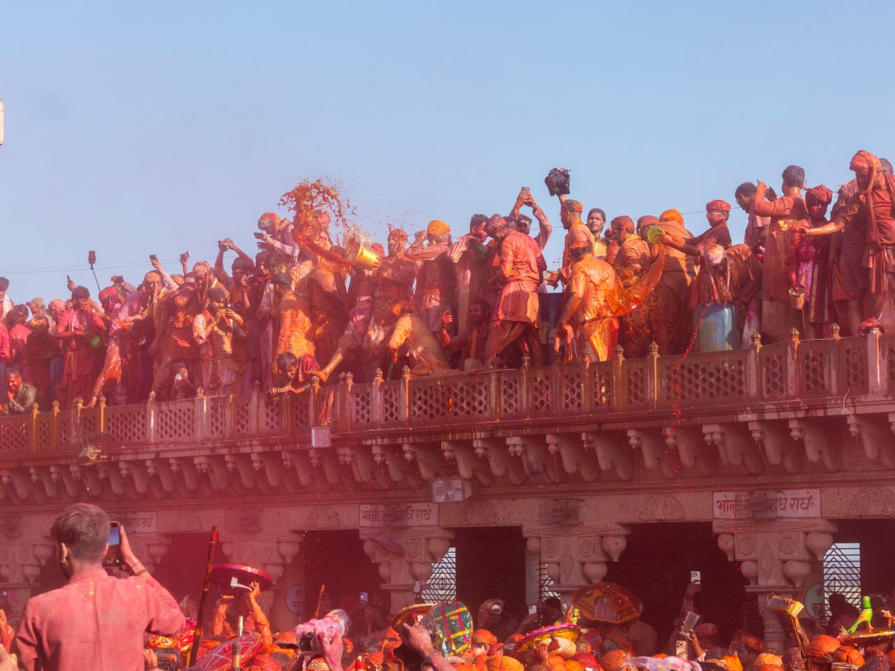 Crowds celebrate Holi with vibrant colors at Nandgaon temple in India.